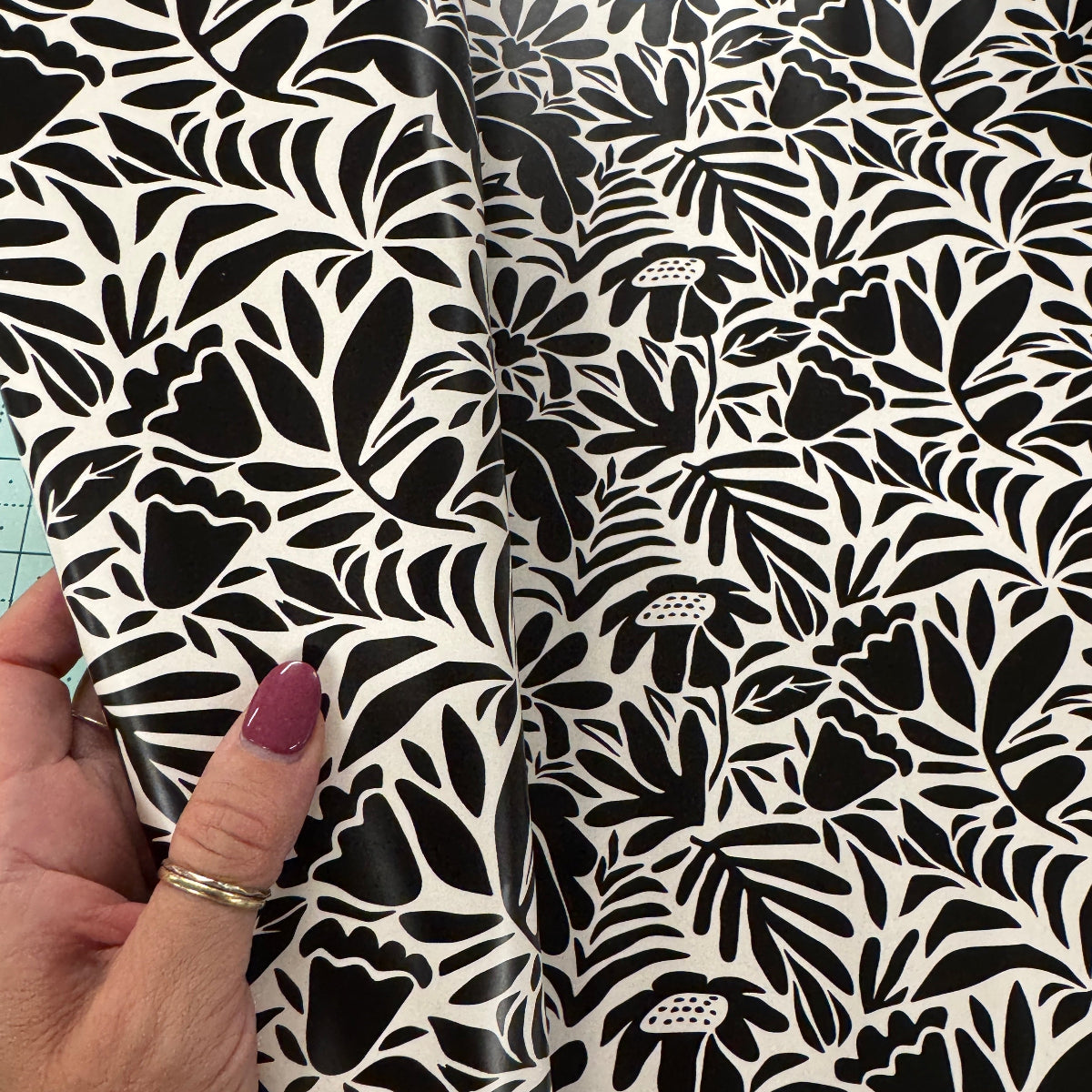 Black and white floral patterned fabric held by a hand